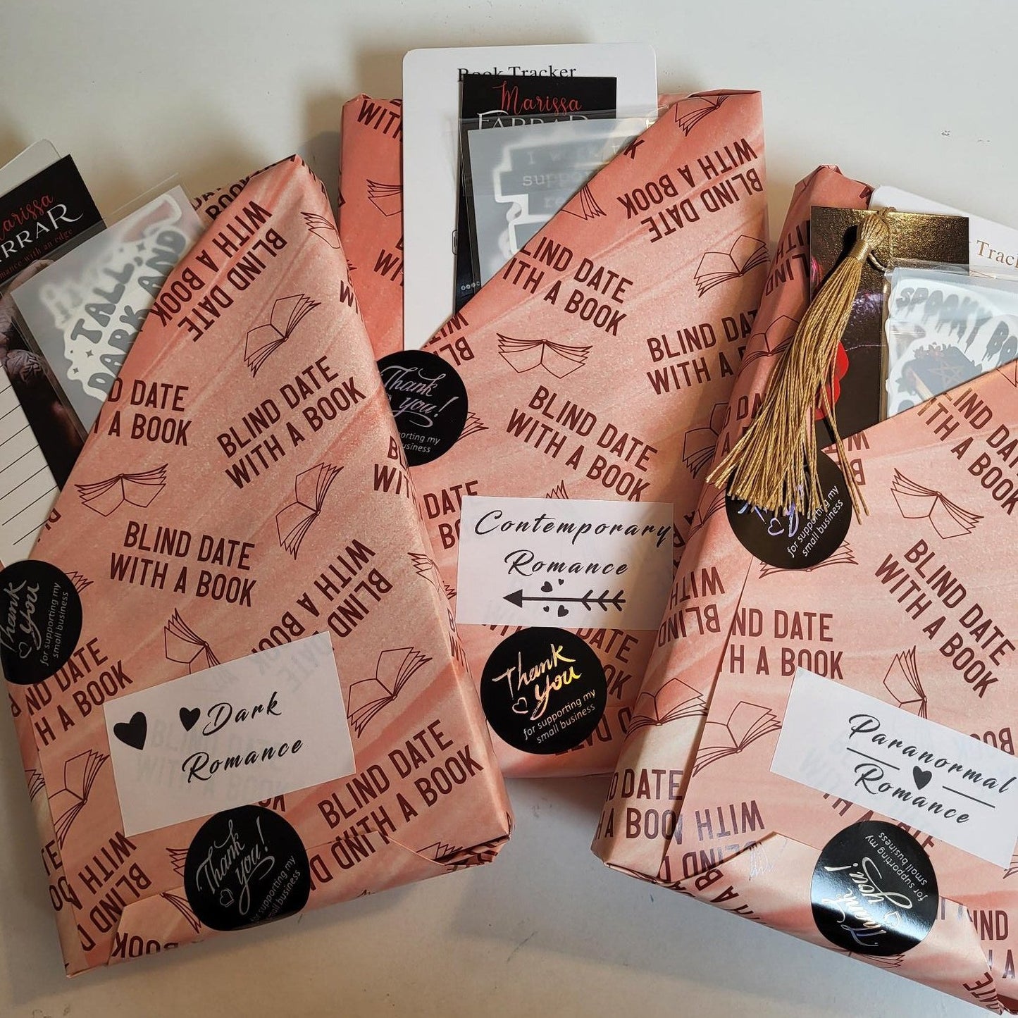 Three wrapped 'Blind Date with a Book' books showing genres of paranormal romance, dark romance, and contemporary romance.