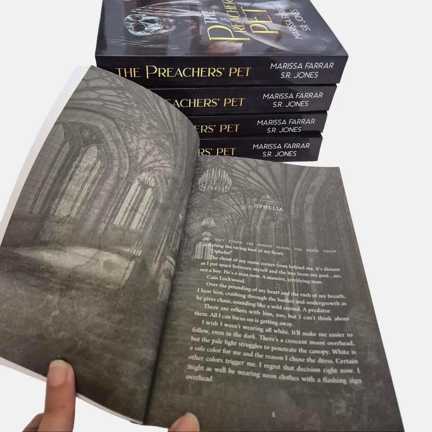 interior formatting of the paperback of The Preachers' Pet by Marissa Farrar and SR Jones, a dark, why choose, college romance. A stack of paperbacks is behind it.