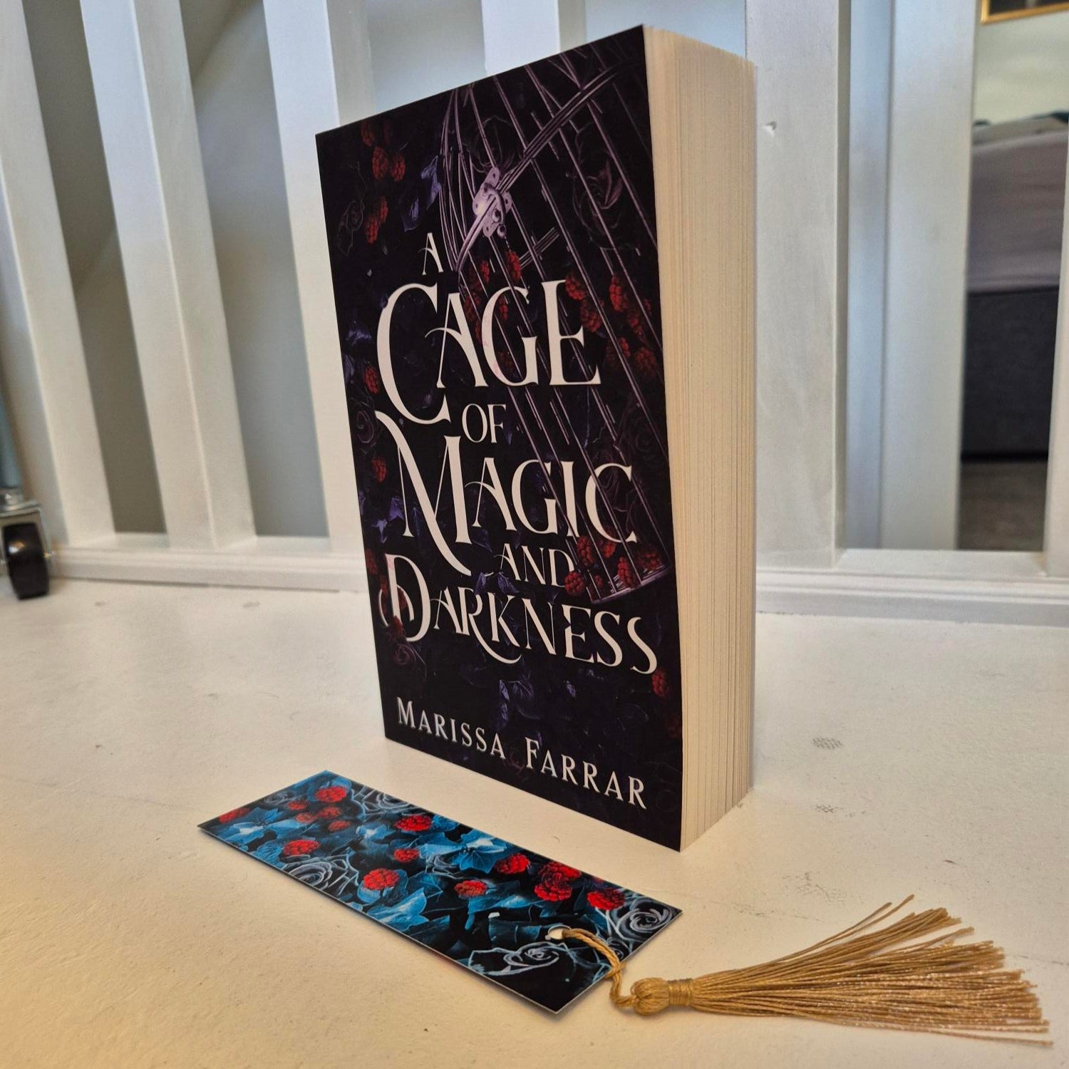 Book titled 'Cage of Magic and Darkness' by Marissa Farrar on a shelf with a bookmark next to it.