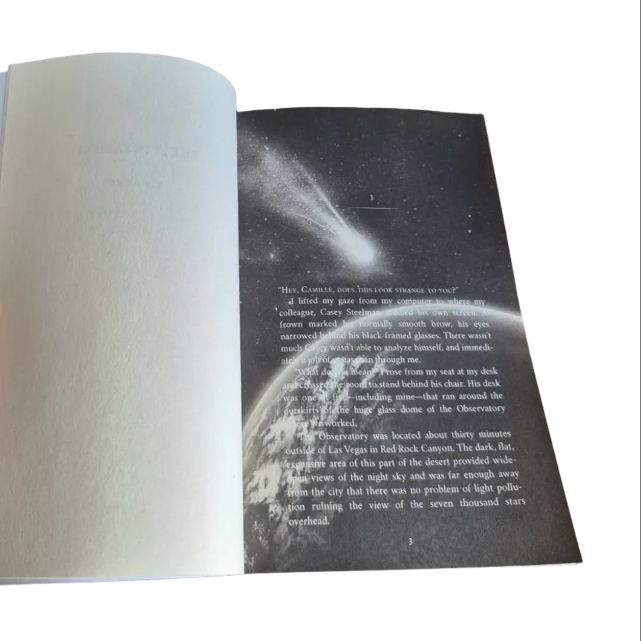 Open book with a space-themed illustration on a wooden surface