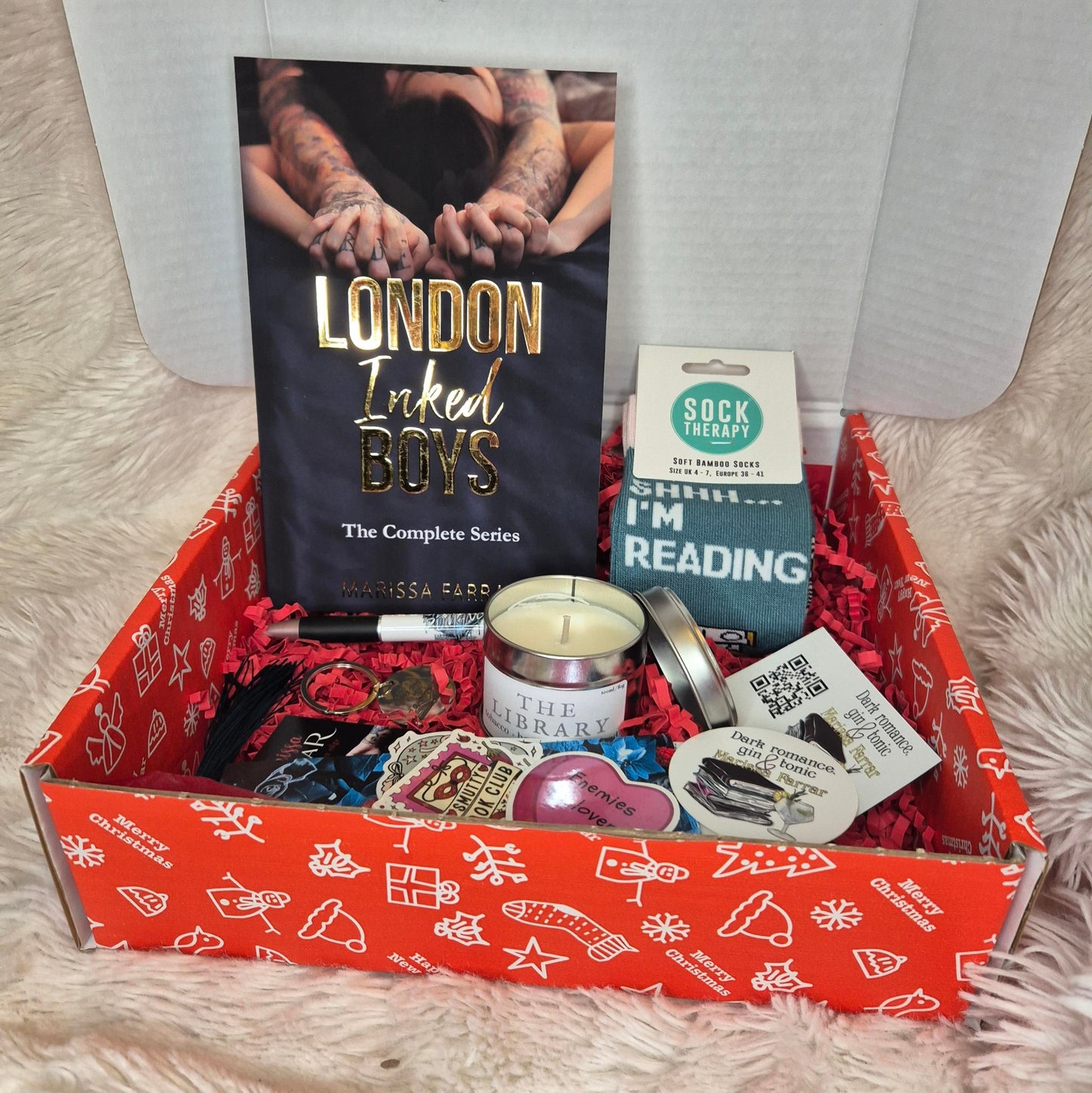 Christmas Box with 'London Inked Boys' book, 'I'm Reading' socks, and other items on a fluffy surface